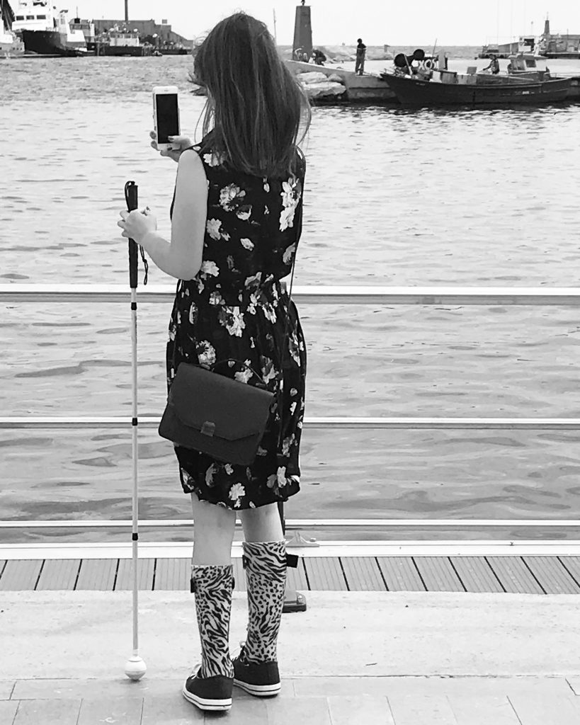 black and white photo of chloe on her phone while holding her cane