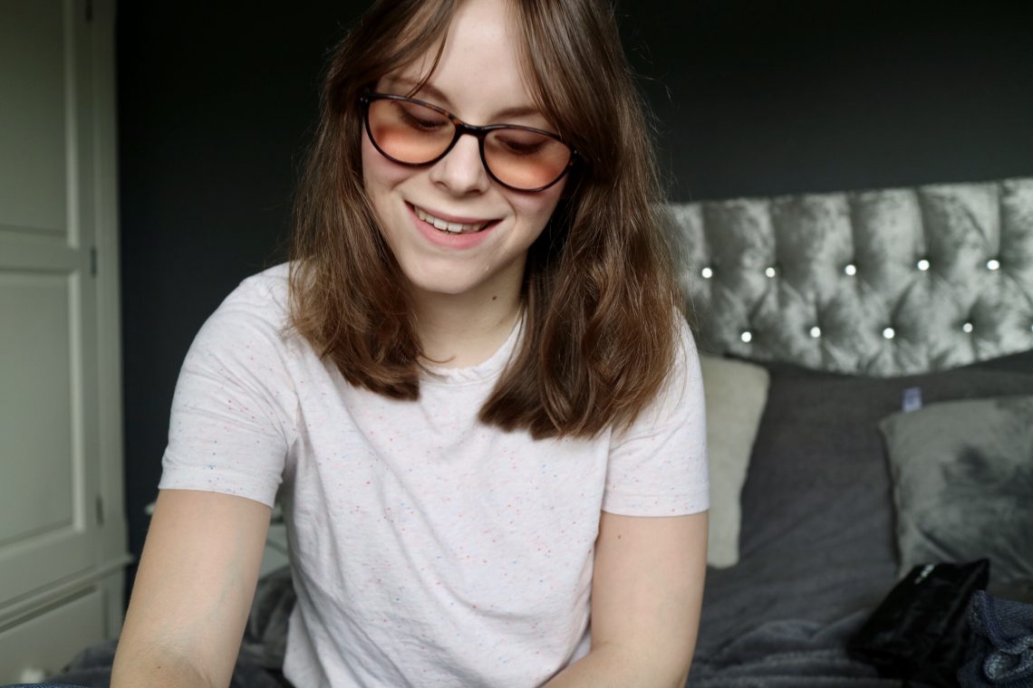 Chloe smiling but looking down. She is wearing white t-shirt