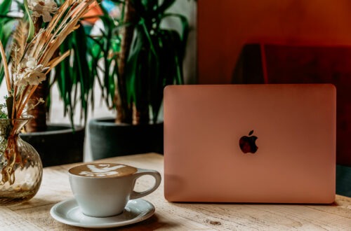 In a cafe. On the table is an open laptop and a cup of coffee